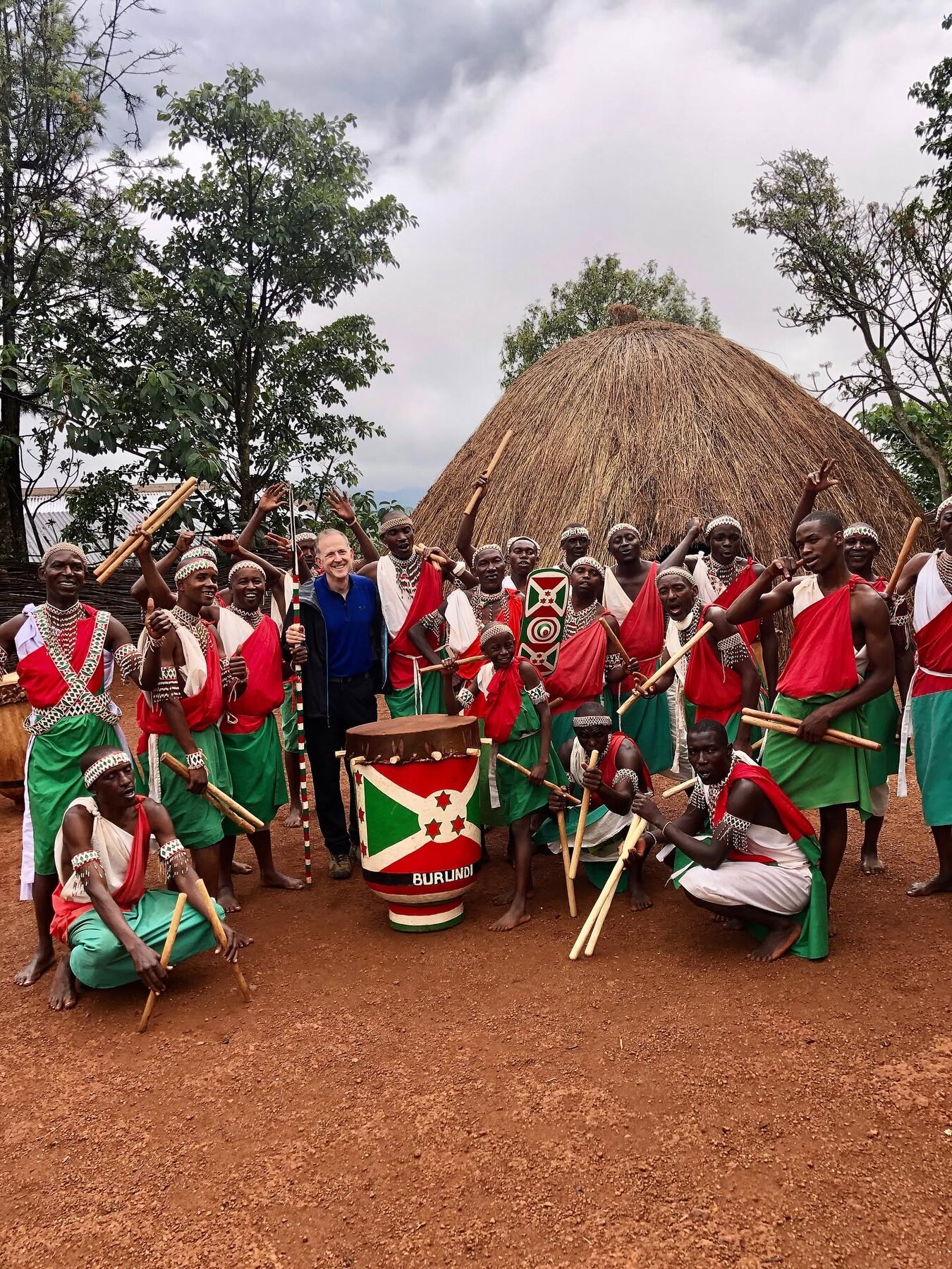 Royal drummers and a visitor gathered in front of Gishora’s traditional hut
